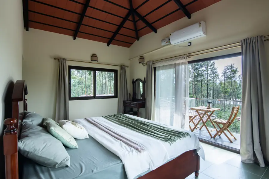 Master bedroom with a carved wooden bed and a door out to a private balcony with chairs
