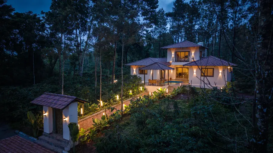 The villa lit at dusk with the gatehouse in front