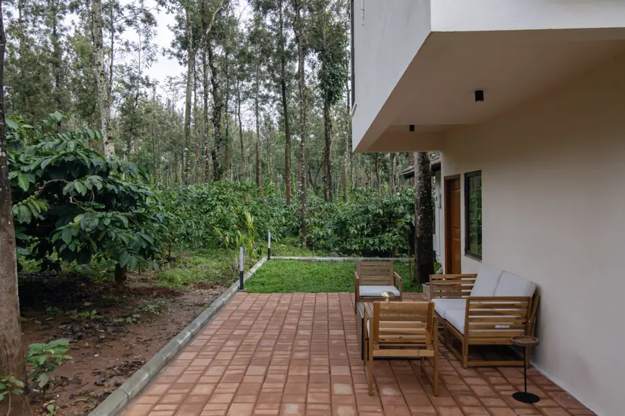 A brick-paved verandah with outdoor chairs facing coffee plants